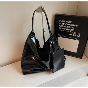 Detail view of black glossy patent leather hobo tote with matching small zip pouch
