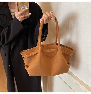 Détail du sac cabas en daim camel montrant la boucle dorée et la texture sur le mannequin