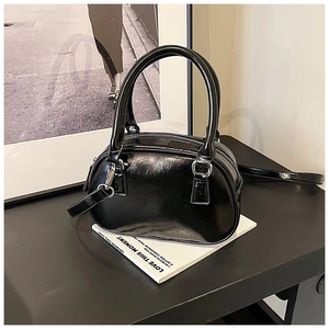 Detail of glossy black Boston bag with silver hardware on decorative book