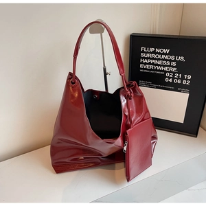 Detail of burgundy patent leather tote bag with glossy texture and matching mini pouch