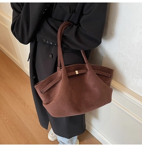 Gros plan d'un cabas en daim moka foncé avec texture mate et détail de boucle latérale