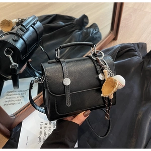 Detail of black PU leather crossbody bag featuring a unique baseball glove bag charm