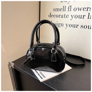 Detail of a black glossy mini bowling bag with silver hardware and dual handles