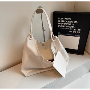 Detail of a minimalist white oversized tote bag with matching mini pouch on a sleek display