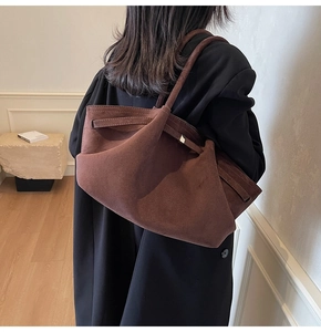 Grand sac cabas marron en daim avec détails de boucles porté par un mannequin en manteau