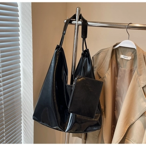 Detail of black glossy leather hobo bag set with a mini square pouch on a hanger