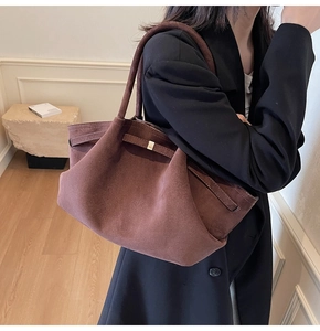 Détail d'un cabas en daim marron foncé avec boucle latérale porté par un mannequin
