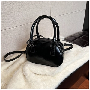 Detail view of black patent leather handbag with silver buckles on white faux fur