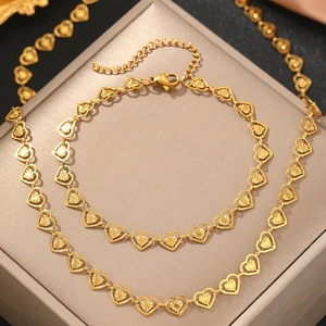 Parure de bijoux cœur dorés avec collier gravé et bracelet sur une boîte d'exposition