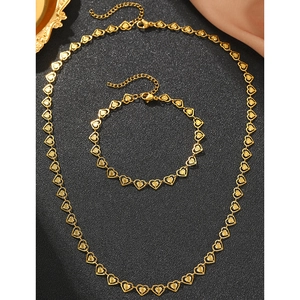 Détail macro de l'ensemble collier et bracelet à maillons cœur dorés sur fond noir