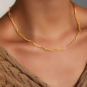 Gros plan d'un collier chaîne trombone doré porté par un mannequin avec maille