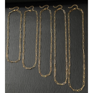 Cinq colliers trombones dorés de différentes longueurs sur fond de cuir noir