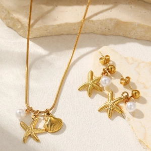 Golden starfish and shell jewelry set with white pearls on a natural stone surface