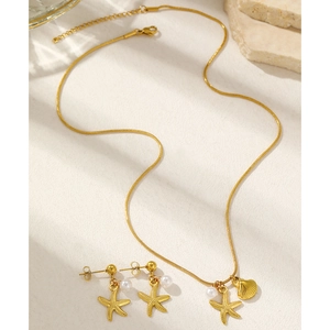 Detail view of gold starfish and shell jewelry set with elegant pearls on a stone background