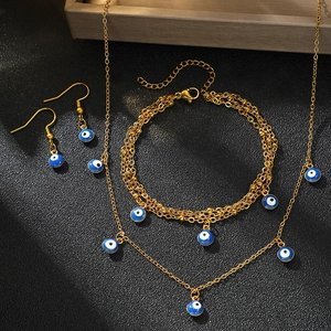 Golden Evil Eye jewelry set including necklace, layered bracelet and earrings on black leather