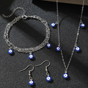 Detailed set of silver stainless steel evil eye necklace, bracelet and earrings on black