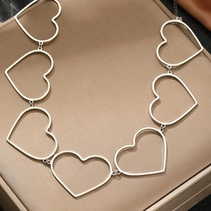 Minimalist silver stainless steel hollow heart chain necklace displayed on silk