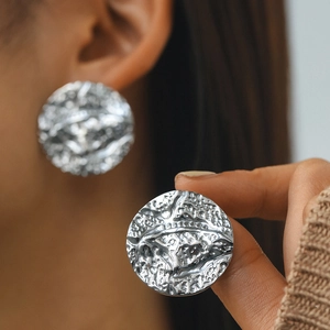 Macro shot of silver textured hoop earrings featuring irregular molten metal lava surface