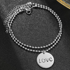Detail eines zweischichtigen Edelstahl-Perlenarmband mit graviertem LOVE Rundanhänger