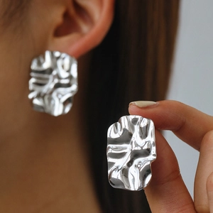 Close-up of square irregular crumpled texture silver earrings on model ear