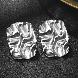 Macro shot of silver square stud earrings with irregular hammered metal texture details