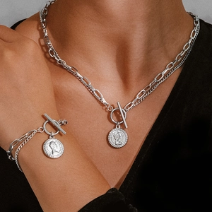Detail of silver layering coin necklace and bracelet set with retro OT toggle clasp