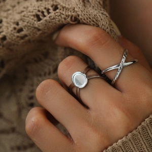 Detail of silver crisscross twisted ring and geometric flat circle band on finger