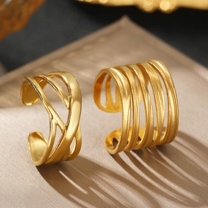 Detailed view of layered gold-plated stainless steel rings with woven and parallel designs