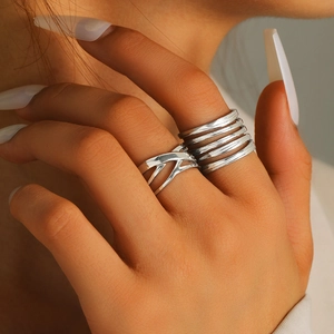Macro shot of silver multi-layer and criss-cross open ring set on a female model