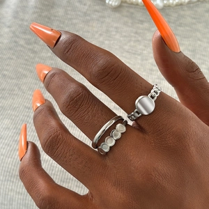 Close-up of double-layer hollow rings and chain ring set on a model with orange nails