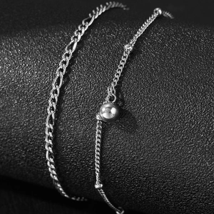 Dettaglio di cavigliera doppia in acciaio inossidabile argento con design Figaro e perle