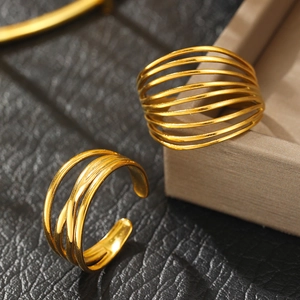 Detail of layered gold open rings with a matte finish on a textured black surface