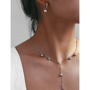 Dettaglio del set collana e orecchini a cerchio in acciaio inox con ciondoli sferici