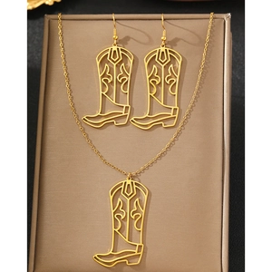 Detail view of hollowed-out western cowboy boot pendants on a brown jewelry display