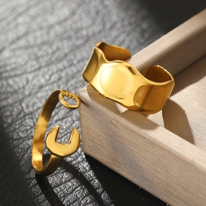 Irregular textured wide band and wrench shaped gold open ring set on a jewelry box