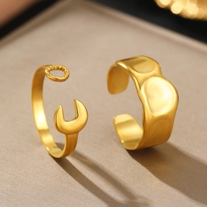 Irregular gold wave ring and creative wrench style adjustable rings set on gray base