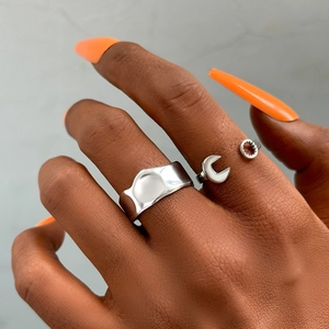 Detail showing irregular wide silver band and creative wrench ring on a hand