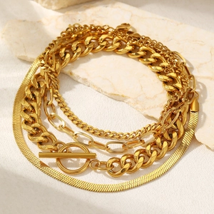 Detail of layered gold snake and cuban link chain set with OT buckle on stone