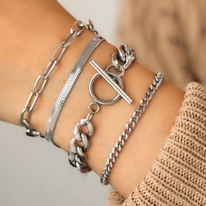 Close-up of four layered stainless steel silver chain bracelets with OT clasp on wrist
