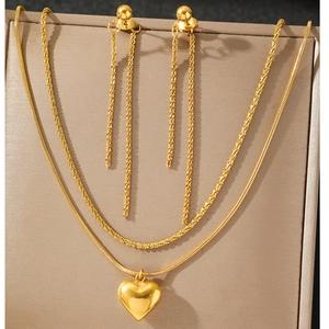 Détail du collier à pendentif cœur doré et des boucles d'oreilles à franges sur présentoir