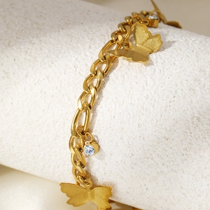 Macro shot of gold butterfly charm with zircon accents on a chunky stainless steel anklet