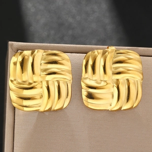 Detailed close-up of square gold stud earrings with textured woven relief patterns