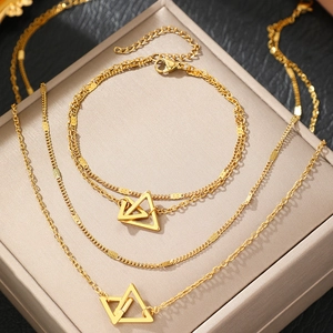 Détail de parure collier et bracelet en acier doré multicouche avec pendentifs triangles