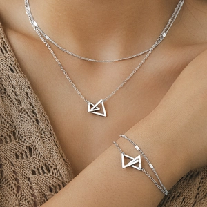 Détail de parure collier et bracelet multicouche en acier avec pendentifs triangulaires