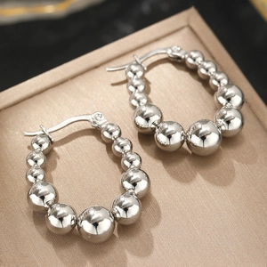 Détail de boucles d'oreilles créoles perlées argentées avec des sphères en métal poli