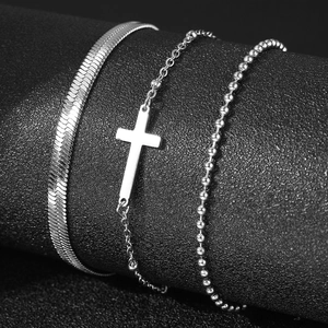 Gros plan sur des chevillières argentées à trois couches avec pendentif croix et perles