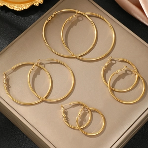 Lot de 4 paires de créoles dorées de tailles variées sur un fond de soie luxueux et élégant