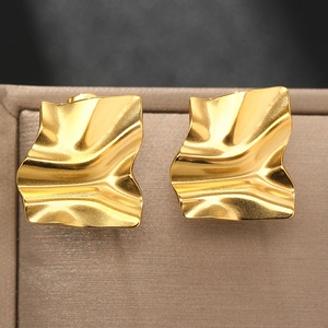 Macro shot of gold square earrings with wavy irregular texture and metallic luster