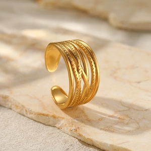 Macro shot of 18K gold plated multi-layer woven ring on a marble stone surface