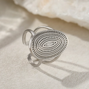 Macro detail of silver adjustable stainless steel ring with textured oval relief pattern